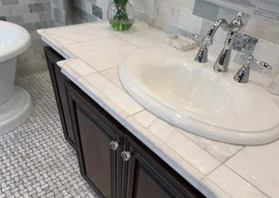Bathroom vanity with marble countertop, dark wood cabinets, and decorative flower arrangement