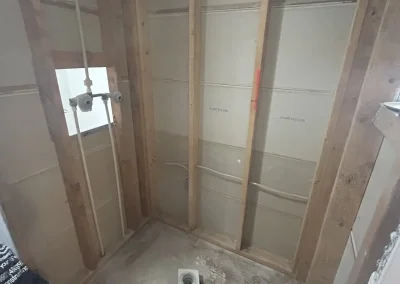 Bathroom shower under renovation with exposed wall studs and plumbing installation