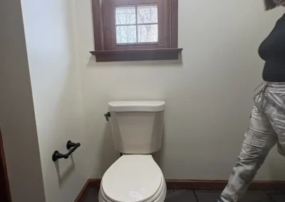 Updated bathroom with toilet beneath window and dark slate tile flooring