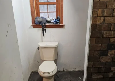 Bathroom before renovation with toilet, unfinished walls, and stone tile flooring