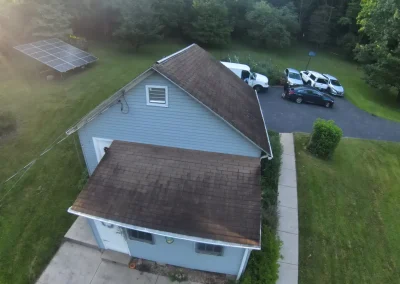 Detached garage with weathered brown shingle roof needing repair