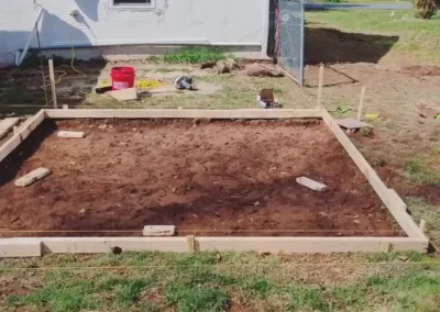 Framed foundation base prepared for concrete pouring beside a residential property.