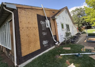 House exterior during renovation showing plywood sheathing and Tyvek HomeWrap ready for new siding installation.