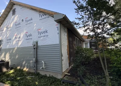 House exterior with Tyvek HomeWrap and partially installed grey vinyl siding during renovation project.