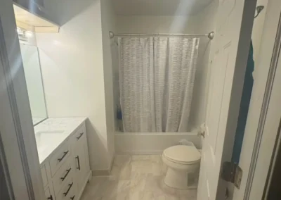 Modern bathroom with white vanity, marble countertop, tiled floor, and shower with curtain.