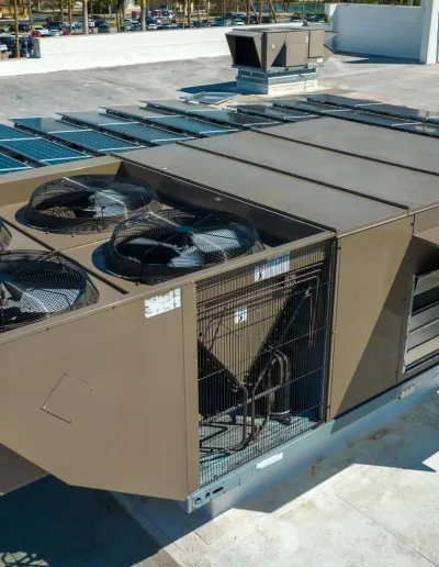 Large rooftop HVAC unit with industrial fans and ductwork, surrounded by solar panels, providing climate control for a commercial or institutional building.