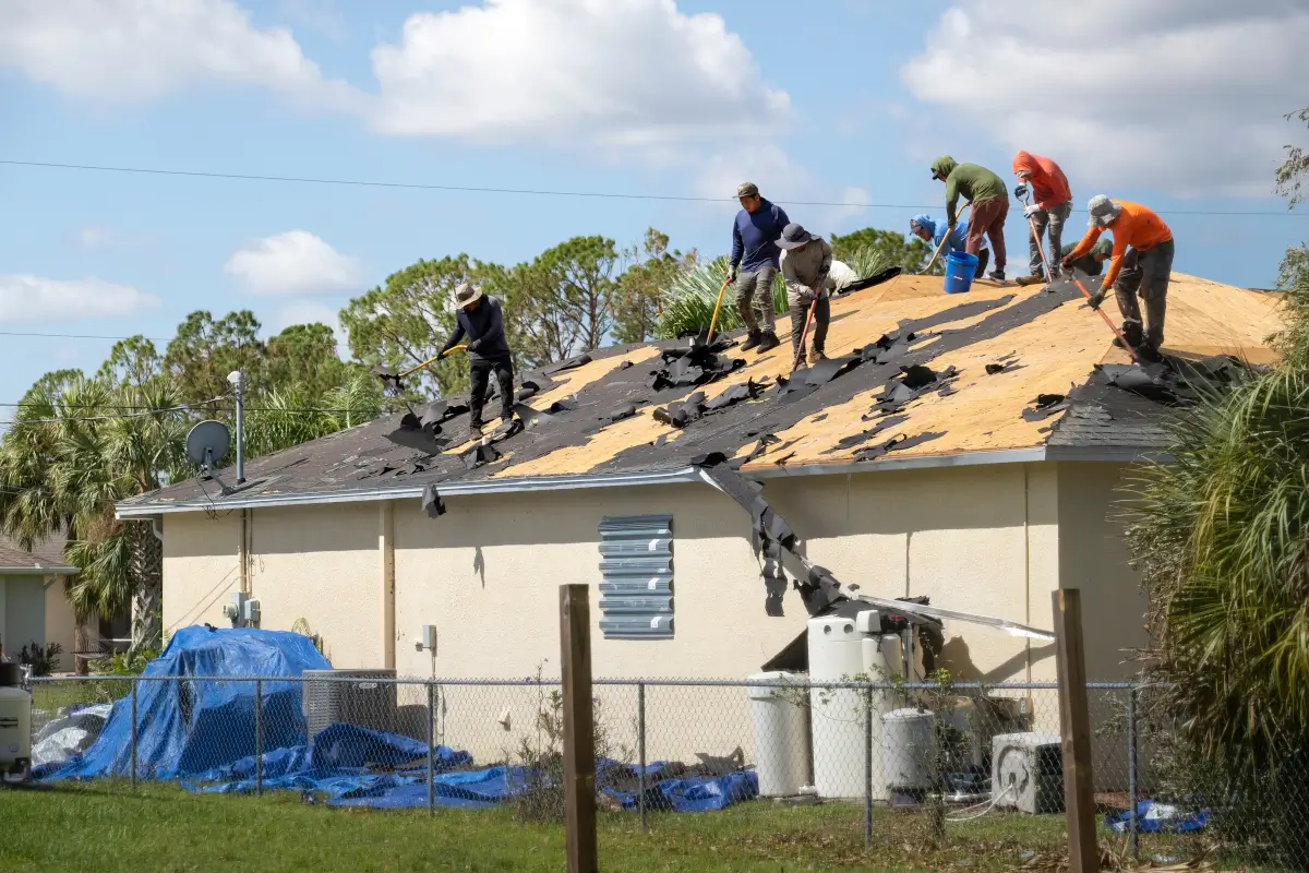 Roofers installing black roof tiles on residential home.