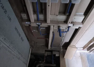 Bathroom plumbing reconfiguration for new custom shower system with exposed PEX lines and valve manifold installation