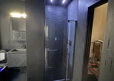 Finished modern black gothic bathroom remodel with custom tile shower and frameless glass door