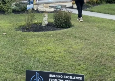 Pinnacle Pro Builders project manager meeting homeowner outside brick house in Berks County PA with kitchen and bathroom remodel yard sign