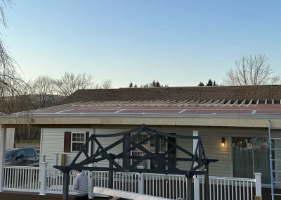 Roof deck addition under construction showing exposed rafters and ZIP System sheathing being installed over an existing home's covered porch area